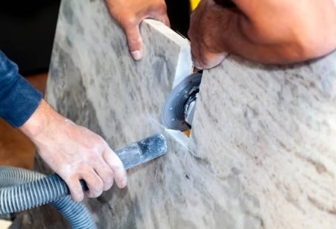 artisan cuts edges in marble kitchen countertop with hand circular saw