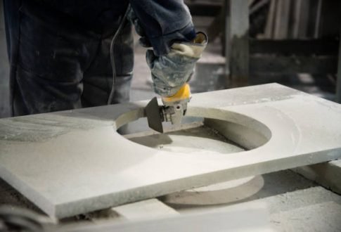 Plant for the processing of natural granite, marble. Man polishing marble stone table by small angle grinder. Stone cutter